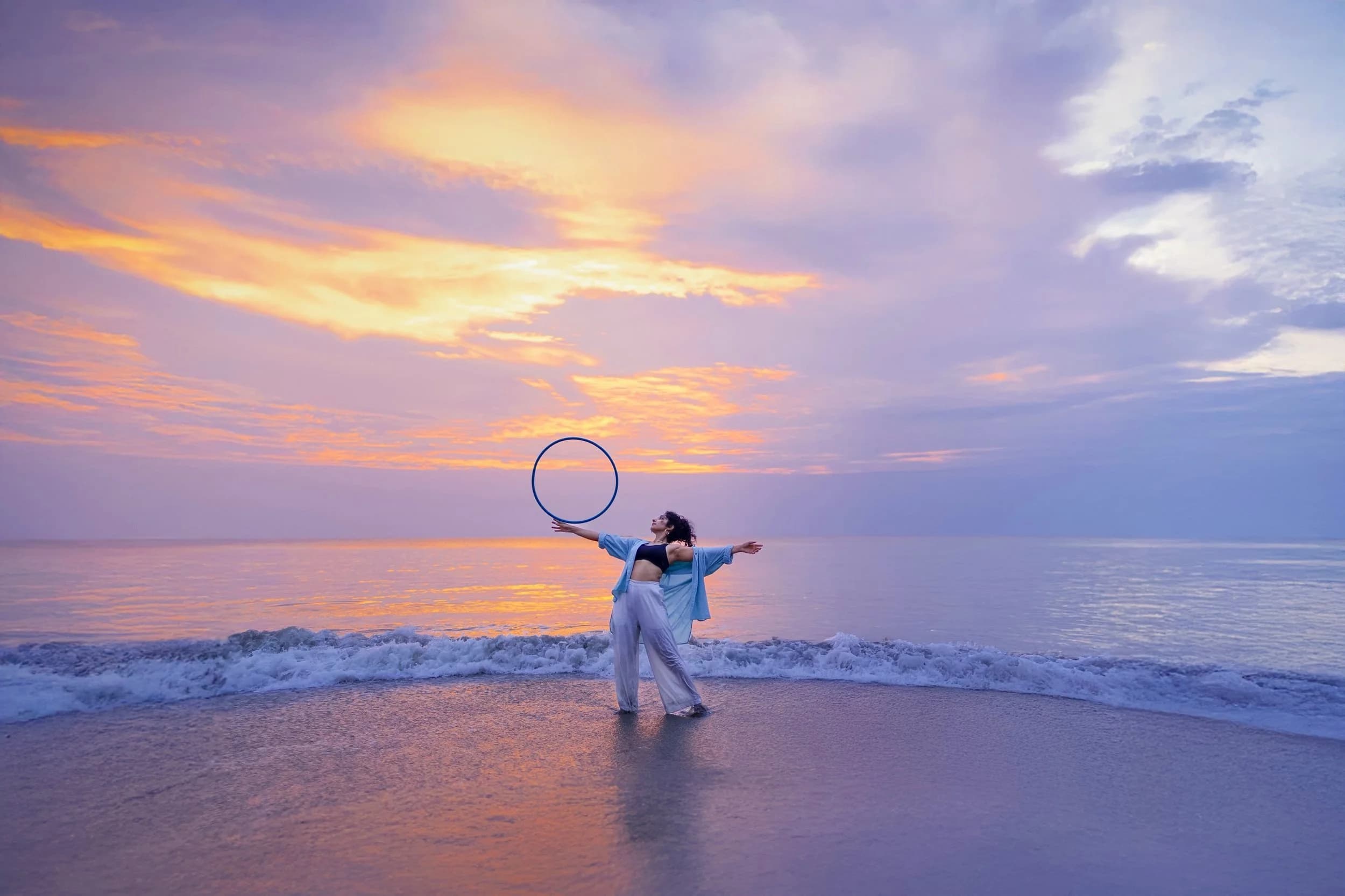 Eshna Kutty holding a hoop on a beach at sunset.